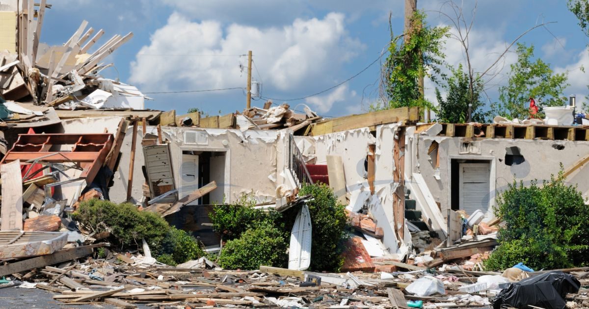 Casa residencial destruída por desastre natural, com escombros e destroços espalhados no terreno